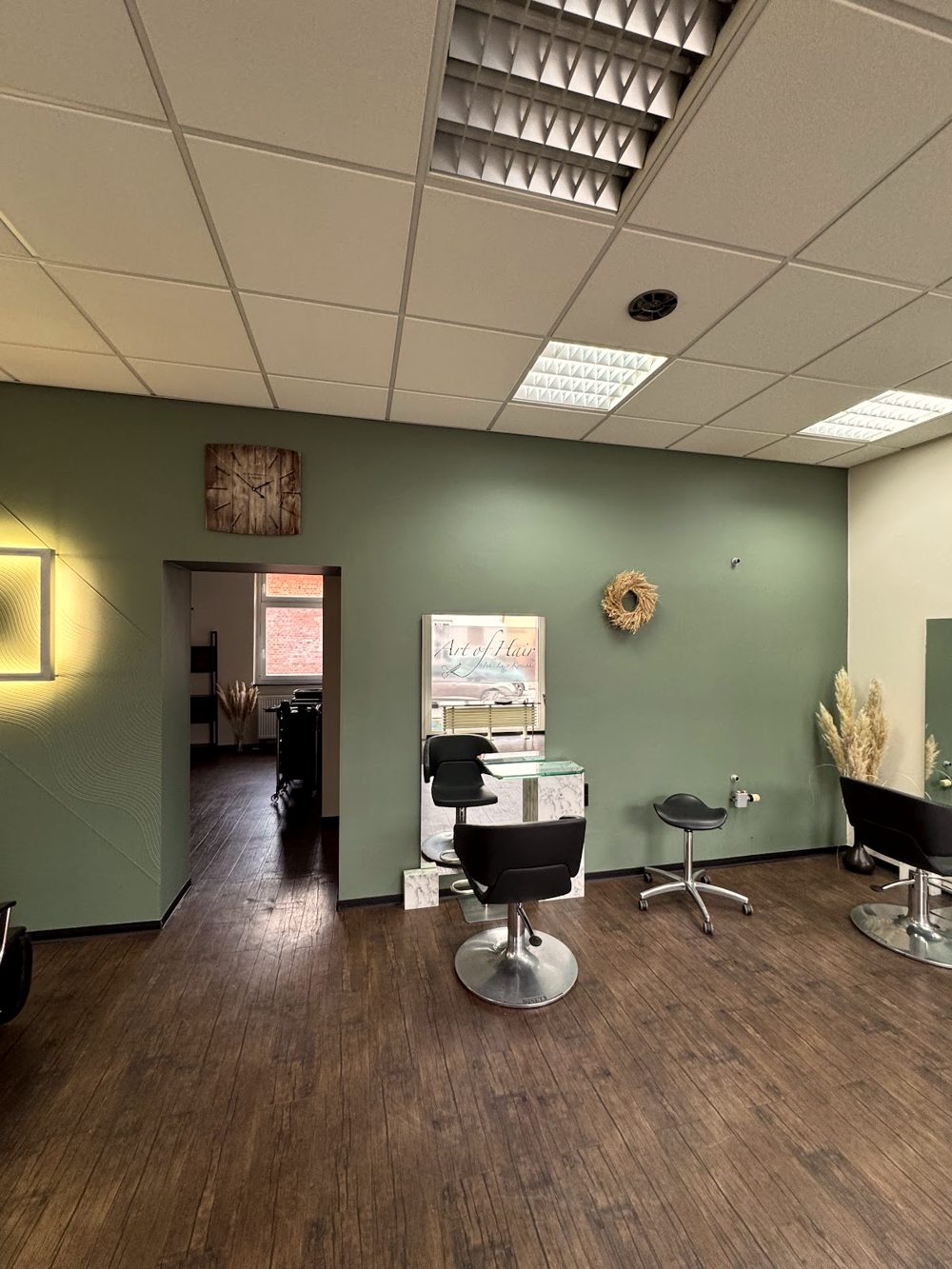 Salbeigrüne Wand, Holzboden und Pampasgras im Salon Art of Hair
